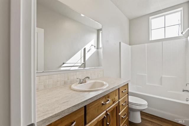 bathroom with vanity, toilet, wood finished floors, and tasteful backsplash