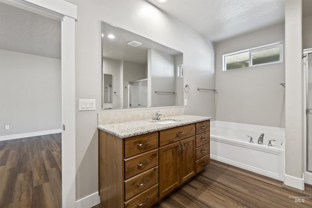 bathroom with backsplash, a stall shower, wood finished floors, a bath, and vanity