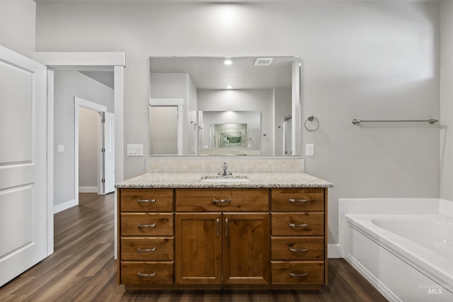 bathroom with tasteful backsplash, wood finished floors, vanity, and a bath