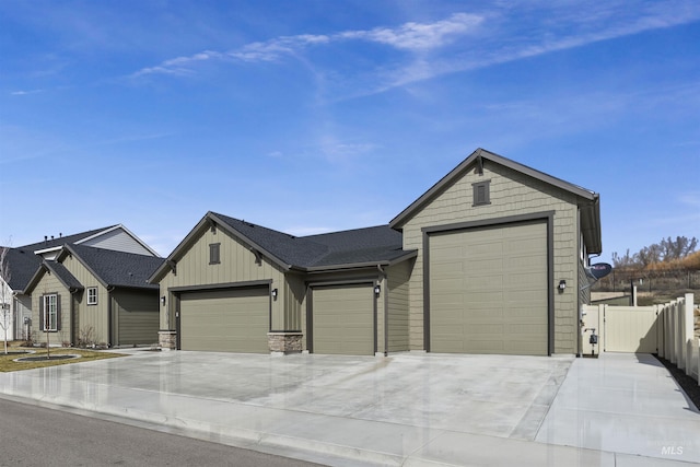 view of front facade with fence, driveway, stone siding, a garage, and board and batten siding