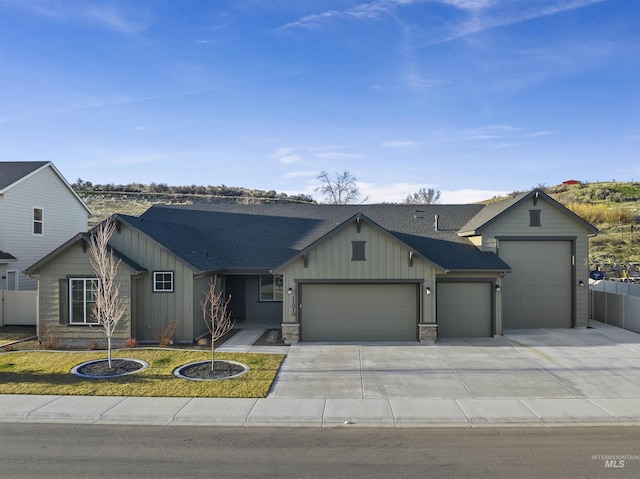 view of front of home featuring board and batten siding, fence, concrete driveway, roof with shingles, and an attached garage