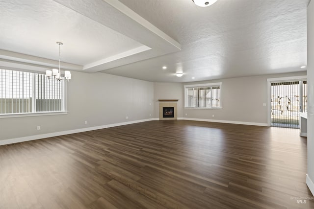 unfurnished living room with a glass covered fireplace, dark wood-type flooring, plenty of natural light, and baseboards