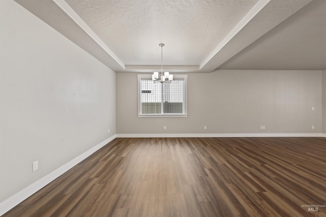 unfurnished room featuring a notable chandelier, baseboards, dark wood-type flooring, and a tray ceiling