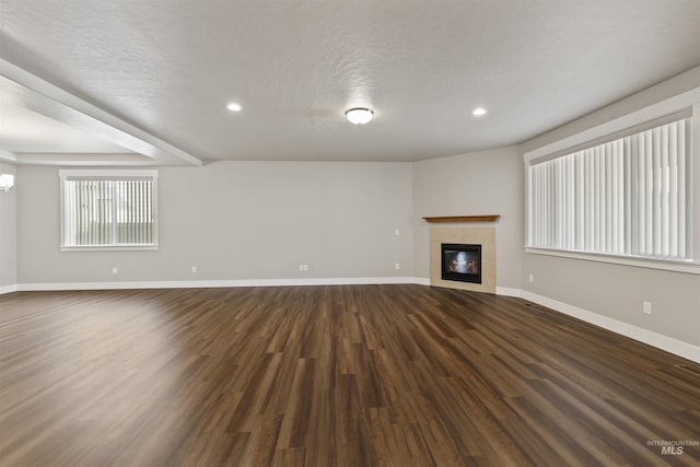 unfurnished living room featuring baseboards, dark wood finished floors, recessed lighting, a fireplace, and a textured ceiling