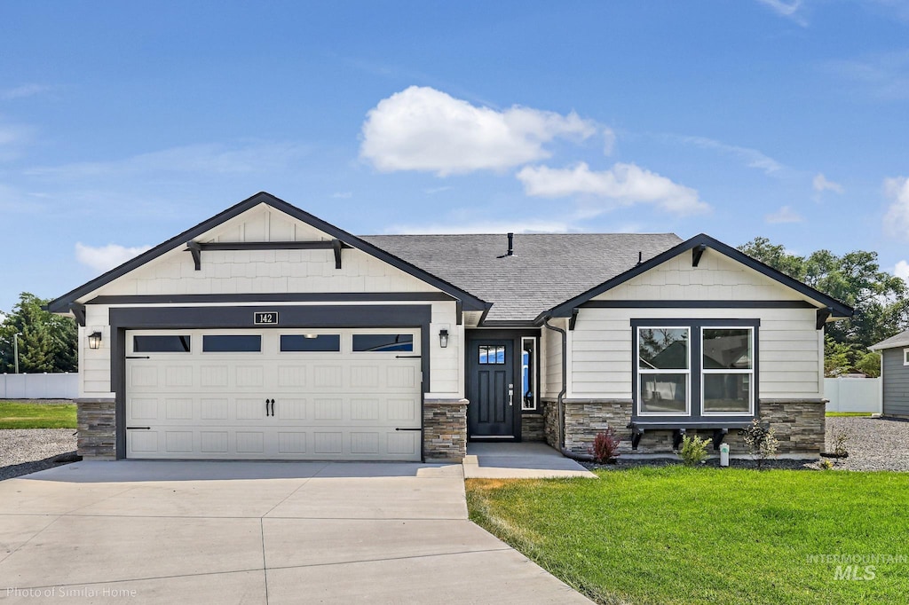 view of front of property featuring stone siding, concrete driveway, a garage, a front yard, and a shingled roof