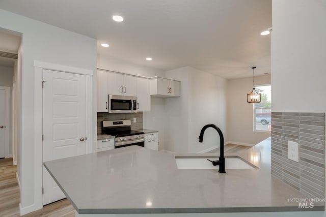 kitchen with stainless steel appliances, light countertops, decorative light fixtures, and white cabinetry