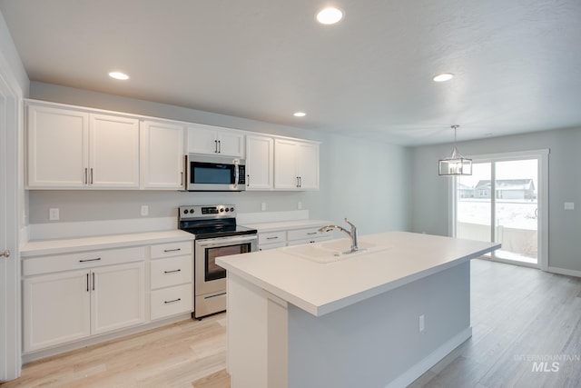 kitchen featuring white cabinets, pendant lighting, stainless steel appliances, light hardwood / wood-style flooring, and sink