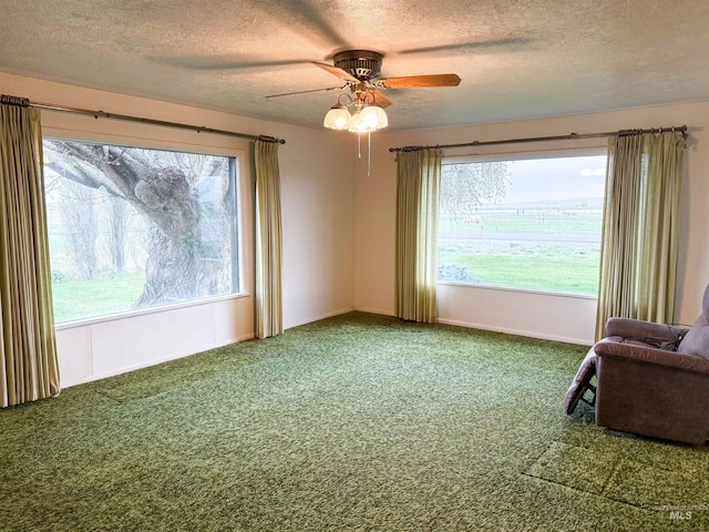 carpeted spare room featuring baseboards, ceiling fan, and a textured ceiling