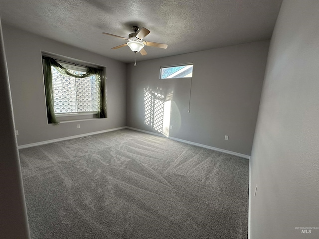 empty room featuring ceiling fan, carpet, and a textured ceiling