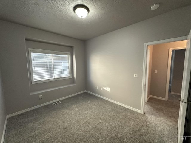 empty room with carpet floors and a textured ceiling