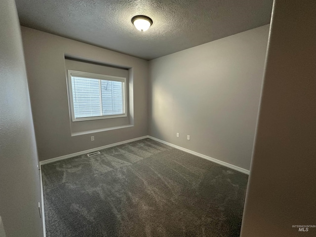 unfurnished room with a textured ceiling and dark carpet