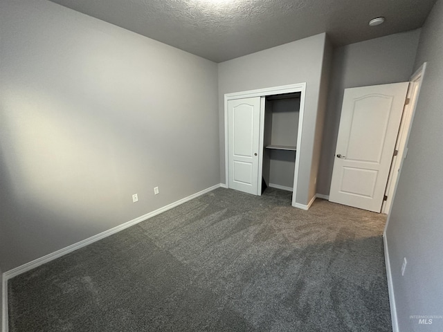 unfurnished bedroom featuring a closet, a textured ceiling, and dark colored carpet