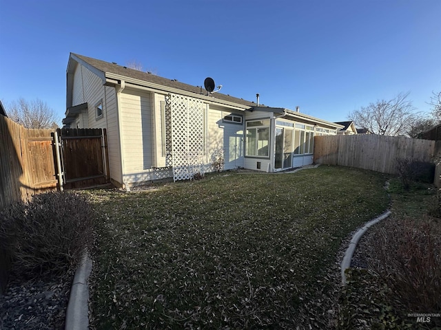 rear view of property featuring a sunroom and a lawn