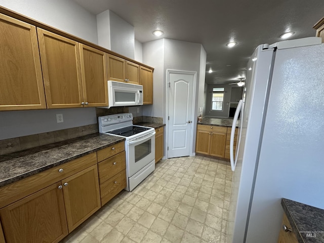 kitchen with ceiling fan, dark stone counters, and white appliances