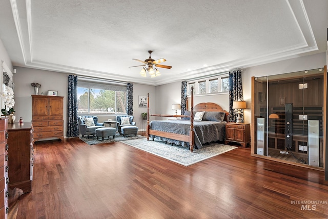 bedroom featuring a tray ceiling, a textured ceiling, and wood finished floors