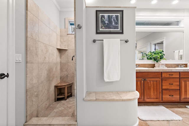 bathroom featuring ornamental molding, recessed lighting, a tile shower, and double vanity