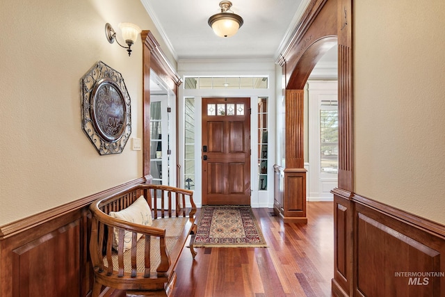 entryway featuring a wainscoted wall, dark wood finished floors, and crown molding