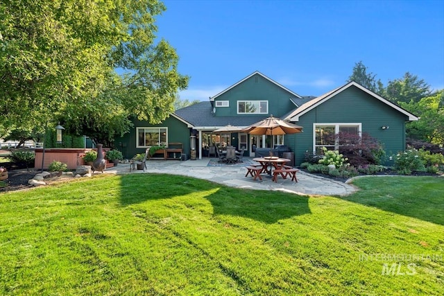 back of house featuring a lawn, a patio area, and a hot tub