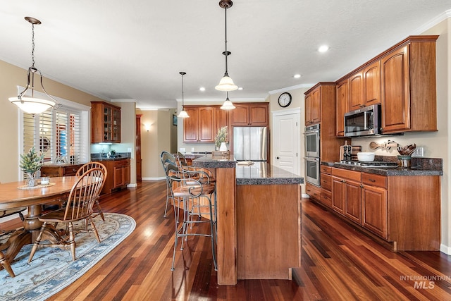 kitchen featuring brown cabinets, ornamental molding, stainless steel appliances, and a kitchen breakfast bar