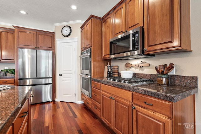 kitchen featuring brown cabinetry, appliances with stainless steel finishes, dark wood-type flooring, and tile counters