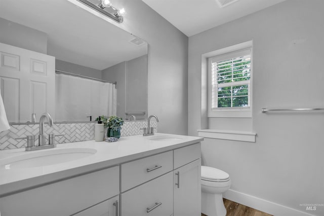 5467 N Claret Cup Way, Meridian, ID 83646 - full bathroom with wood finished floors, double vanity, backsplash, toilet, and baseboards