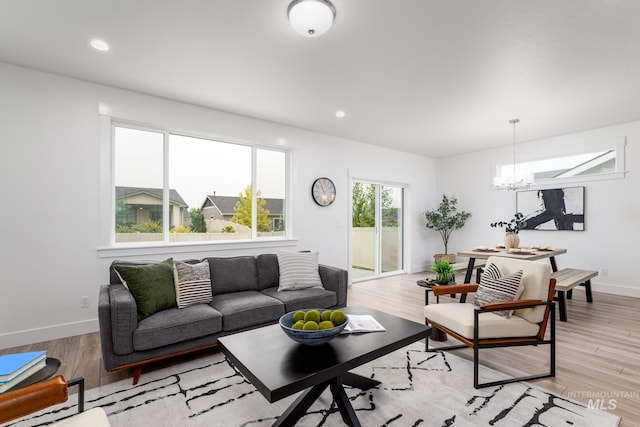 living room with light wood-type flooring, recessed lighting, baseboards, and an inviting chandelier