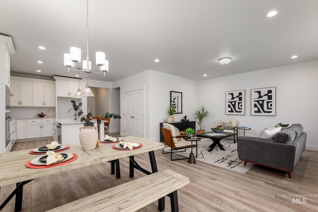 dining room with a chandelier, recessed lighting, light wood-style flooring, and baseboards