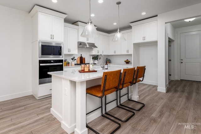 kitchen featuring stainless steel appliances, light countertops, backsplash, white cabinets, and under cabinet range hood