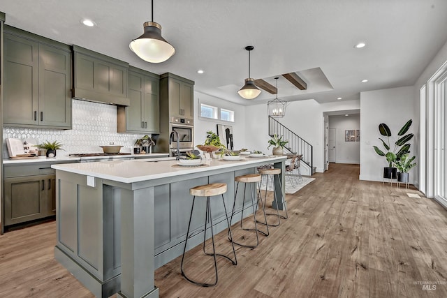 11844 N 21st Ave, Boise, ID 83714 - kitchen featuring light wood-style flooring, light countertops, tasteful backsplash, a center island with sink, and recessed lighting