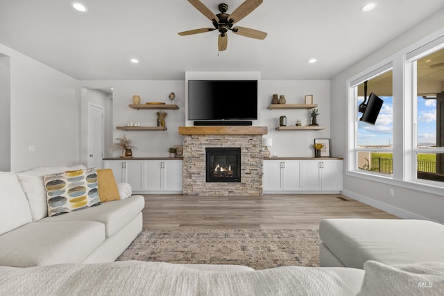 living room with a fireplace, ceiling fan, and light hardwood / wood-style floors