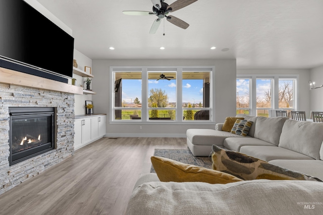 living room featuring light wood-type flooring, built in features, and a fireplace