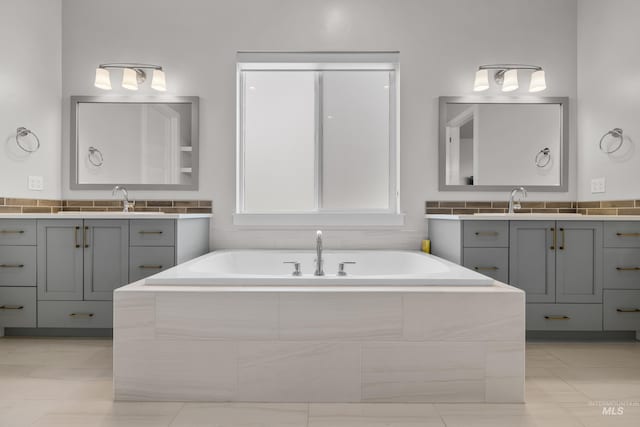 bathroom with tiled tub, tile patterned floors, and vanity