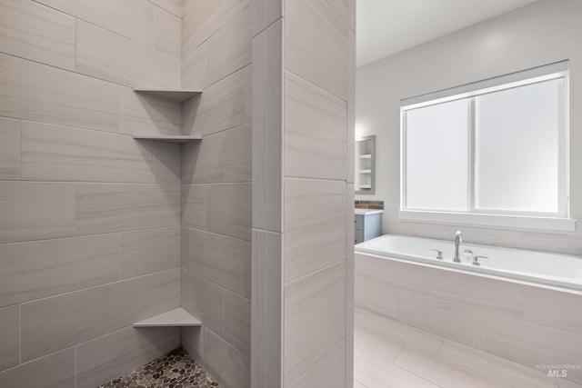 bathroom featuring vanity and tiled tub