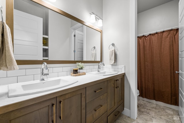 bathroom with toilet, vanity, and tasteful backsplash