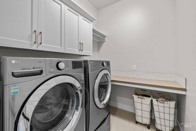 washroom featuring cabinets and washer and clothes dryer