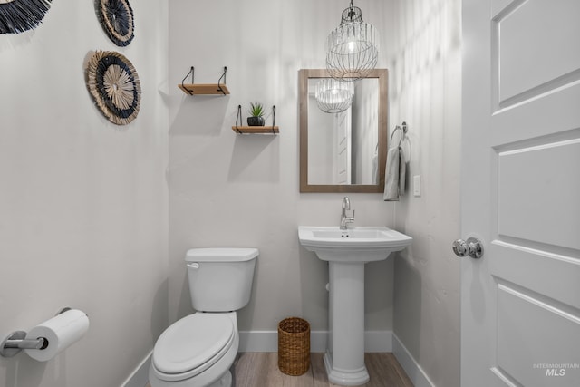 bathroom with sink, an inviting chandelier, and toilet