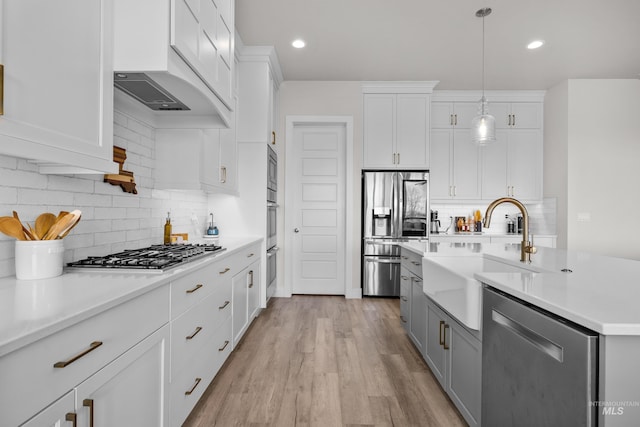 kitchen featuring sink, stainless steel appliances, white cabinets, and hanging light fixtures