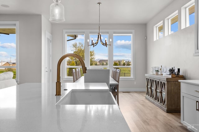 dining room with sink, a chandelier, and light hardwood / wood-style flooring