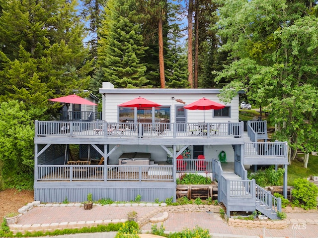 rear view of house featuring a wooden deck and a hot tub