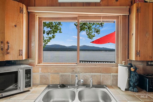 interior details featuring a water and mountain view, tile counters, and sink