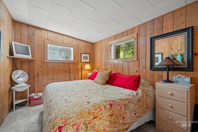 carpeted bedroom featuring wood walls