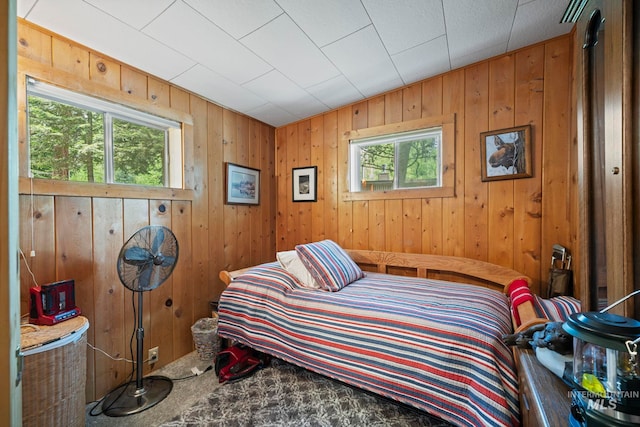 bedroom featuring carpet, multiple windows, and wooden walls