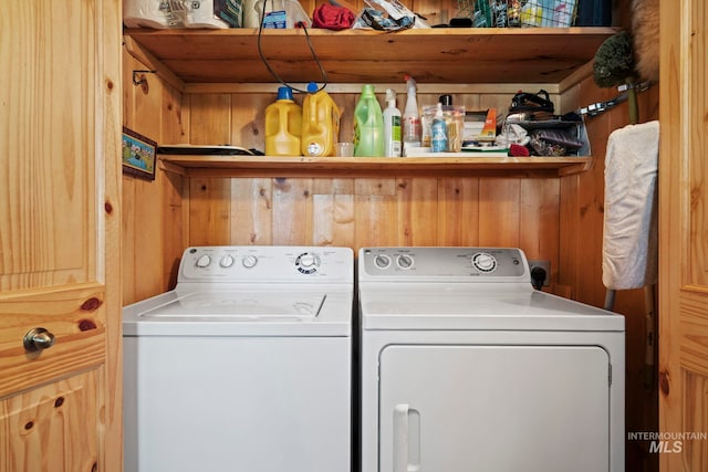 washroom with washer and clothes dryer and wood walls