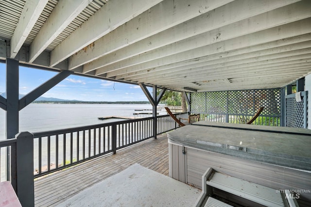 deck with a water view and a hot tub