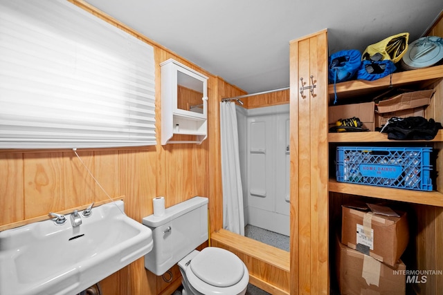 bathroom with a shower with curtain, toilet, wood walls, and sink