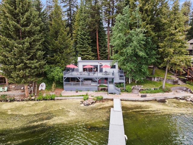 back of property featuring a yard and a deck with water view