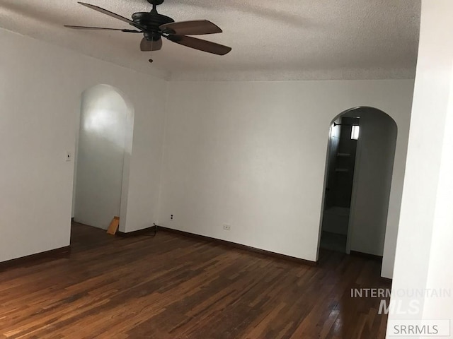 empty room with ceiling fan, dark hardwood / wood-style flooring, and a textured ceiling