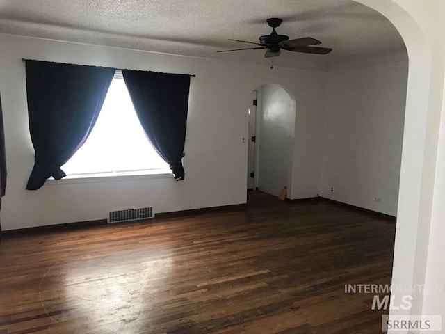 empty room featuring ceiling fan, a textured ceiling, and dark wood-type flooring