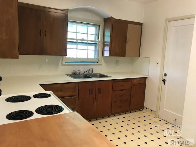 kitchen with electric range, dark brown cabinetry, and sink