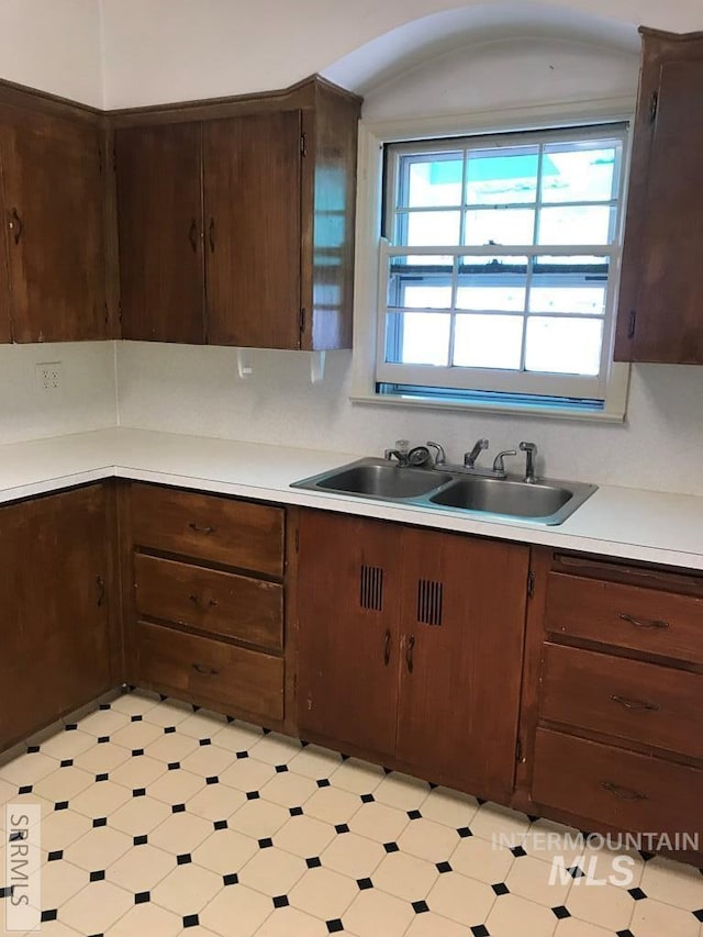 kitchen with dark brown cabinetry, sink, and tasteful backsplash